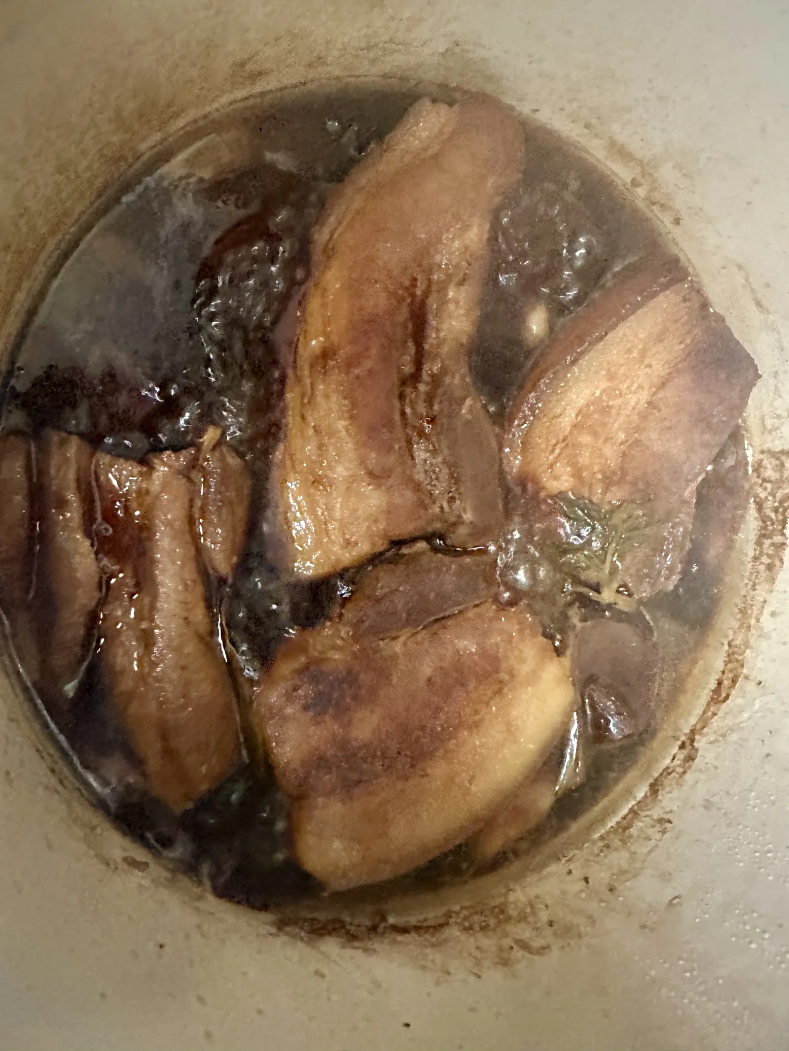 Pork belly braising in the pot, sauce turning deep red and glossy